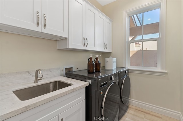 clothes washing area with sink, cabinets, separate washer and dryer, and light hardwood / wood-style floors