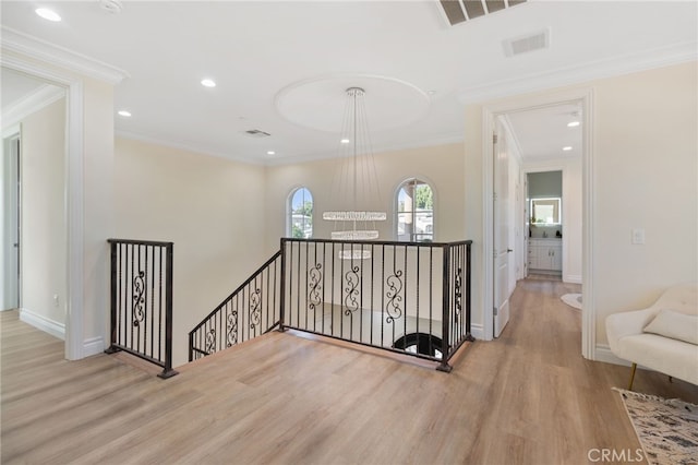 corridor with light hardwood / wood-style floors and crown molding