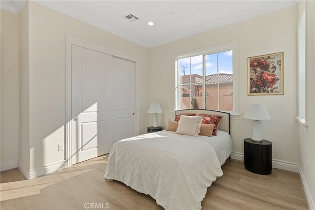 bedroom featuring ornamental molding, a closet, and light hardwood / wood-style flooring