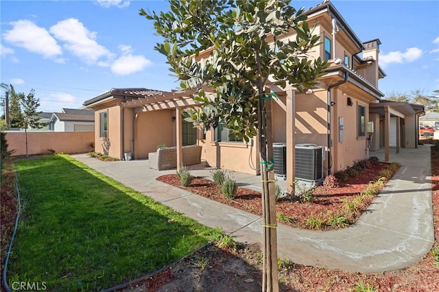 view of front of house featuring central air condition unit, a front lawn, a patio, a garage, and a pergola