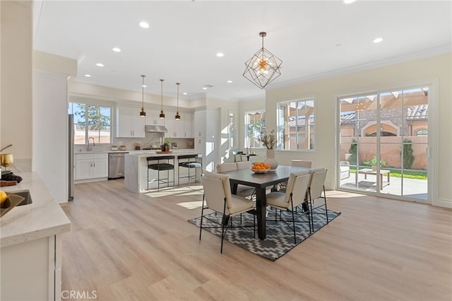 dining room with sink, light hardwood / wood-style floors, and crown molding