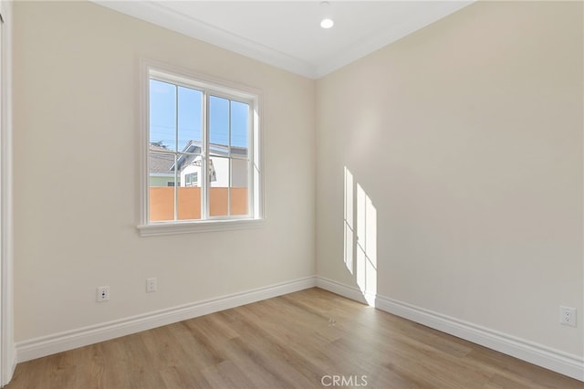 empty room featuring light wood-type flooring and crown molding