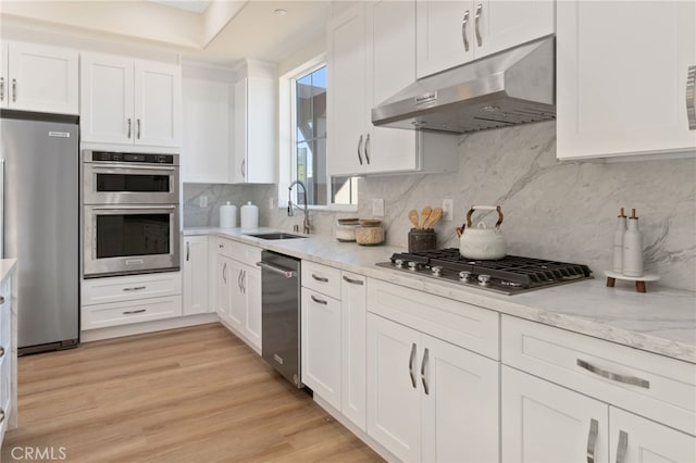 kitchen featuring sink, stainless steel appliances, white cabinetry, and tasteful backsplash