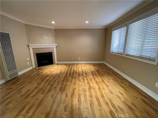 unfurnished living room with crown molding, light hardwood / wood-style floors, and a tiled fireplace