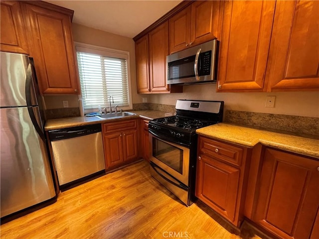 kitchen with sink, appliances with stainless steel finishes, and light hardwood / wood-style flooring