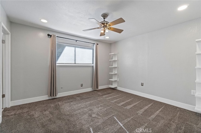 spare room with ceiling fan and dark carpet