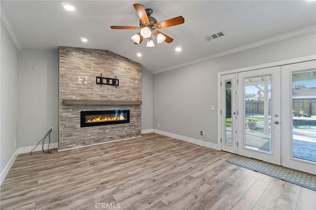 unfurnished living room featuring ceiling fan, a fireplace, french doors, vaulted ceiling, and ornamental molding