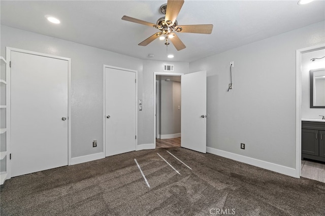 unfurnished bedroom with ceiling fan, connected bathroom, and dark colored carpet