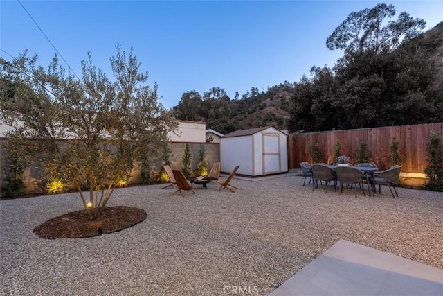 view of yard featuring a fire pit, a patio, and a storage shed