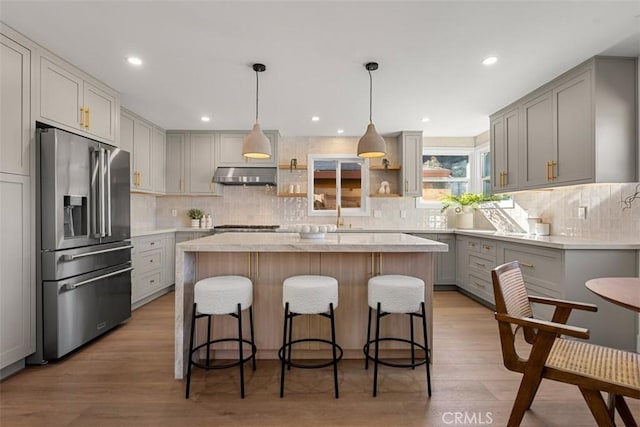 kitchen with gray cabinetry, light wood-type flooring, a center island, and high quality fridge