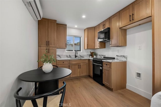 kitchen featuring black appliances, light wood-type flooring, sink, and an AC wall unit