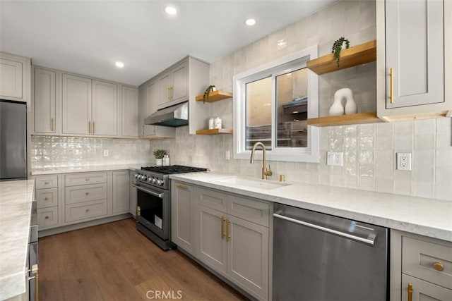 kitchen with sink, appliances with stainless steel finishes, light stone countertops, gray cabinetry, and dark wood-type flooring