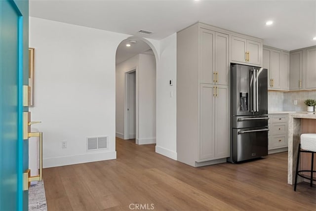 kitchen with a breakfast bar, high end fridge, light hardwood / wood-style flooring, and tasteful backsplash