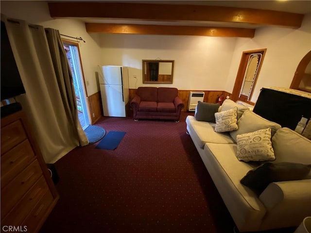 carpeted living room featuring heating unit, wood walls, and beamed ceiling