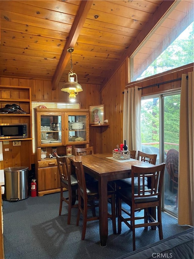 dining space featuring carpet floors, wooden walls, wood ceiling, and vaulted ceiling with beams