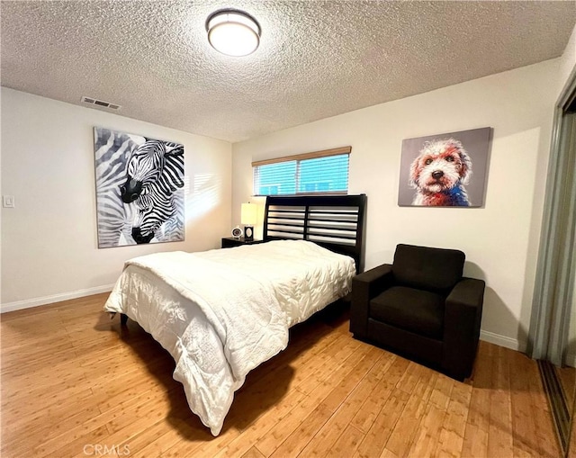 bedroom with light hardwood / wood-style floors and a textured ceiling