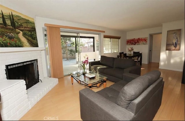 living room with a brick fireplace and wood-type flooring