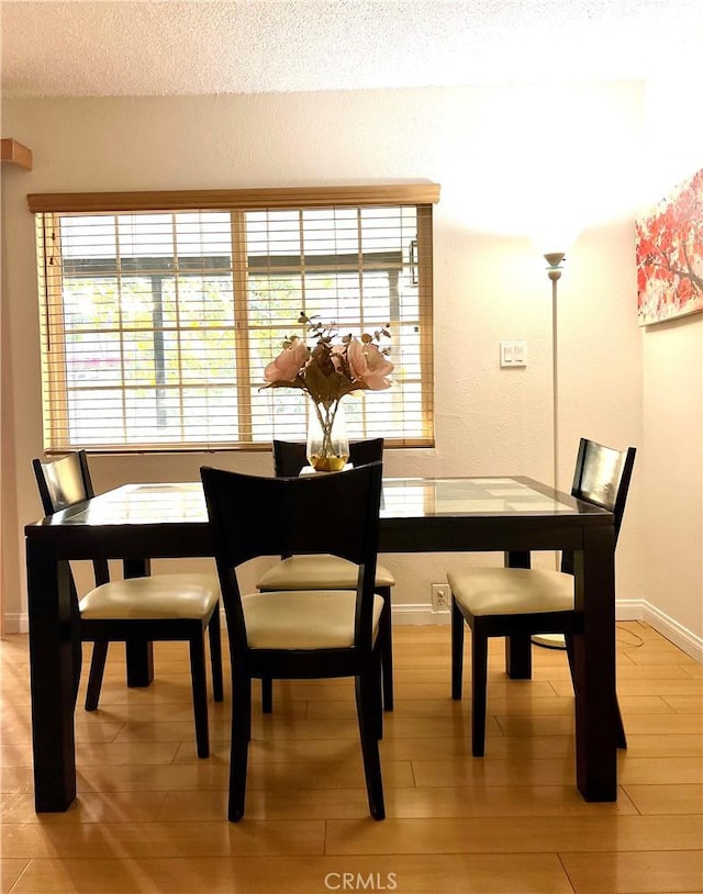 dining space featuring a textured ceiling and light hardwood / wood-style flooring