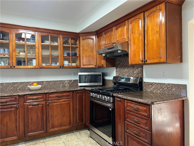 kitchen with stainless steel appliances, dark stone countertops, and decorative backsplash