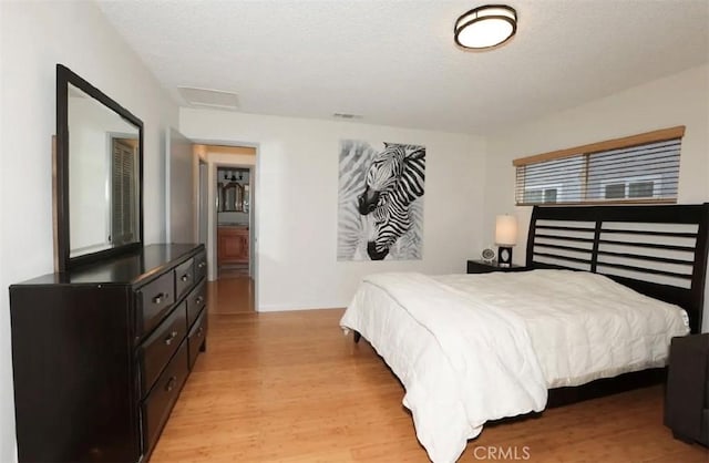 bedroom with ensuite bath and light wood-type flooring