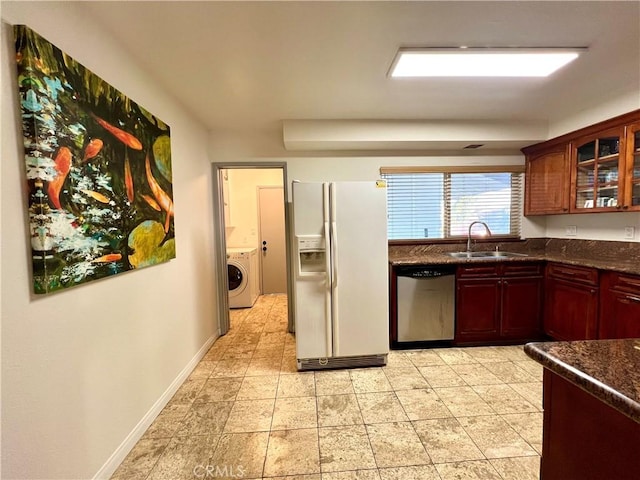 kitchen with dishwasher, washer / clothes dryer, sink, white refrigerator with ice dispenser, and dark stone counters