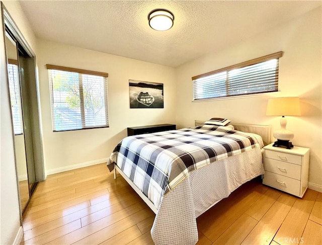 bedroom with a textured ceiling and light wood-type flooring