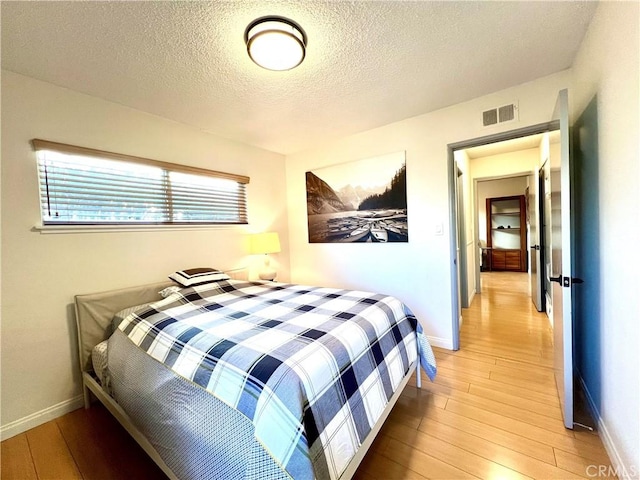 bedroom featuring a textured ceiling and light hardwood / wood-style flooring