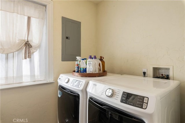 clothes washing area featuring electric panel, a healthy amount of sunlight, and washer and clothes dryer