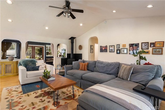 living room with ceiling fan, light hardwood / wood-style flooring, and vaulted ceiling