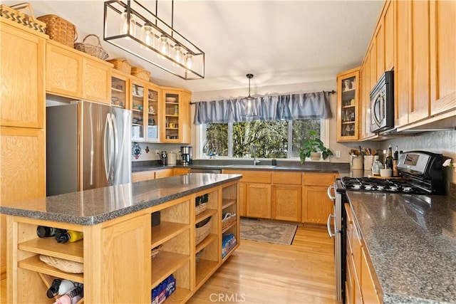 kitchen featuring decorative light fixtures, light hardwood / wood-style floors, stainless steel appliances, and a kitchen island