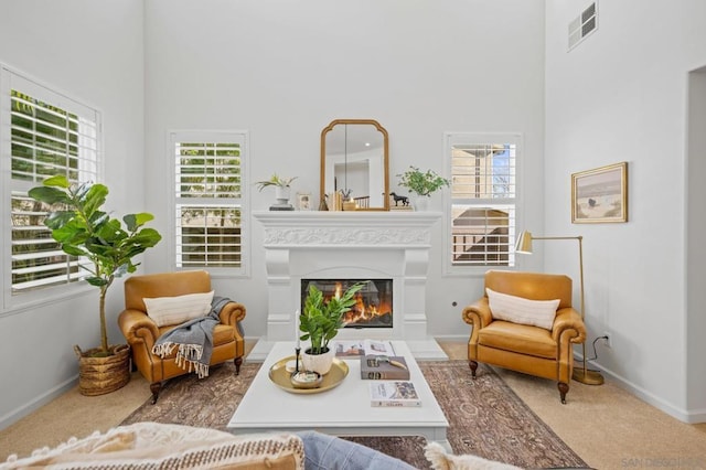 living area featuring a high ceiling and carpet floors