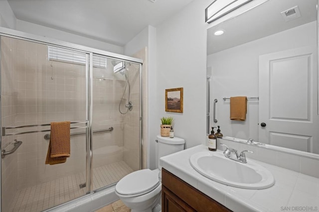 bathroom featuring toilet, a shower with door, vanity, and tile patterned floors