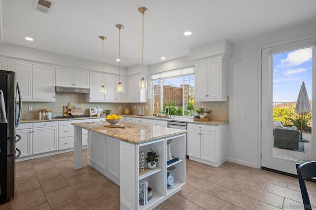 kitchen with appliances with stainless steel finishes, pendant lighting, a kitchen island, white cabinets, and sink