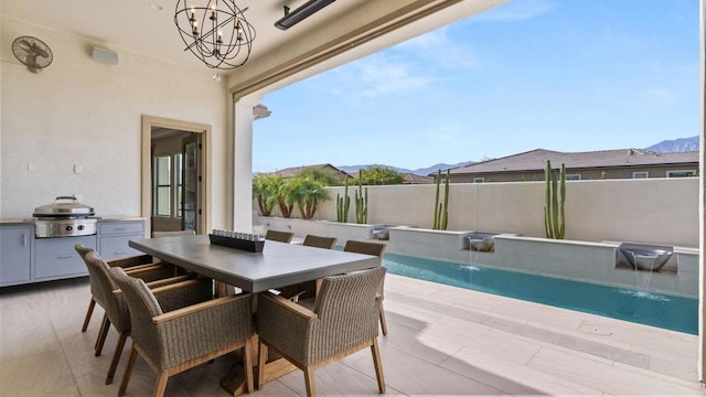 view of patio / terrace featuring area for grilling, a fenced in pool, a mountain view, and pool water feature