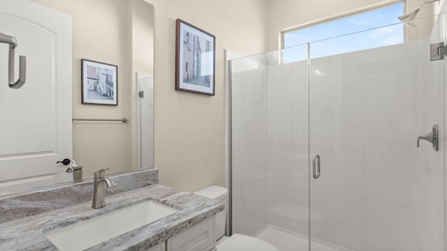 bathroom featuring vanity, toilet, and a shower with door