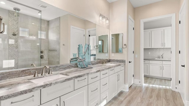 bathroom with vanity, an enclosed shower, hardwood / wood-style floors, and decorative backsplash