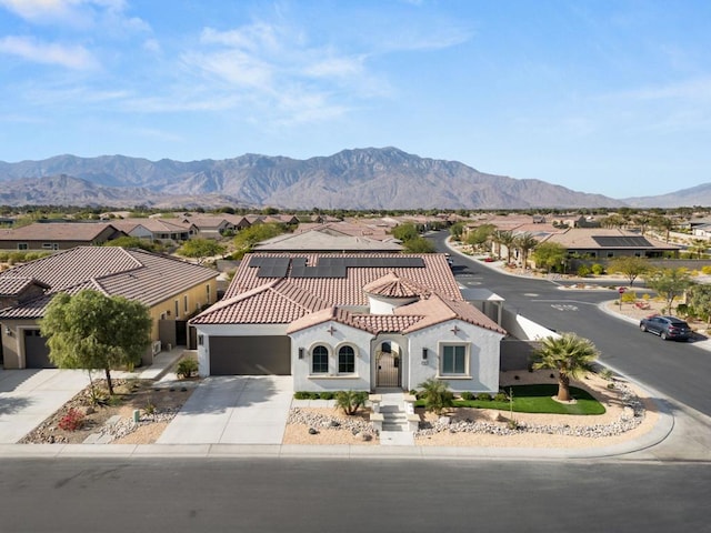 view of front of home with a garage, a mountain view, and solar panels