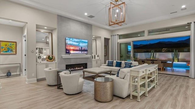 living room featuring a tile fireplace, light hardwood / wood-style floors, and a chandelier