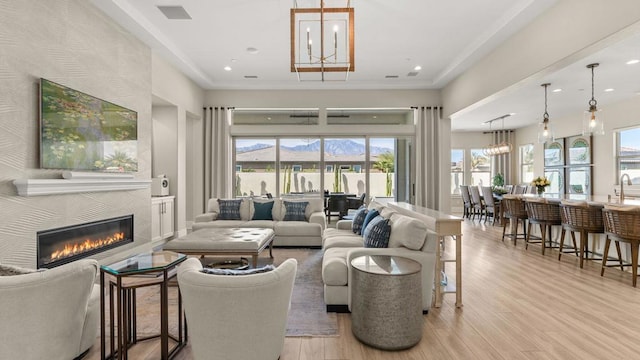 living room featuring a tile fireplace, a mountain view, a notable chandelier, and light hardwood / wood-style flooring