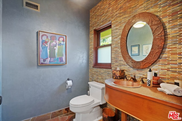 bathroom with vanity, backsplash, and toilet