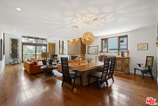 dining area featuring dark hardwood / wood-style flooring and a stone fireplace