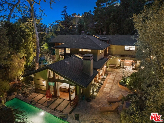 back house at night featuring a patio