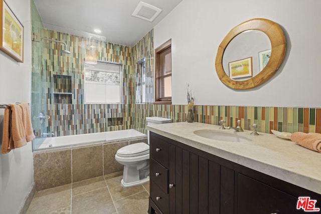 full bathroom featuring tile patterned flooring, tiled shower / bath, vanity, and toilet