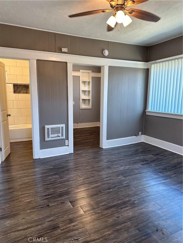 empty room featuring a textured ceiling, ceiling fan, heating unit, and dark hardwood / wood-style floors