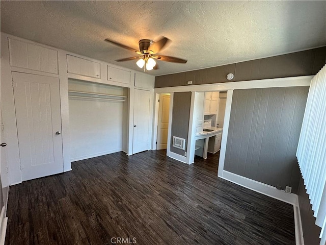 unfurnished bedroom with ceiling fan, a closet, dark hardwood / wood-style flooring, and a textured ceiling