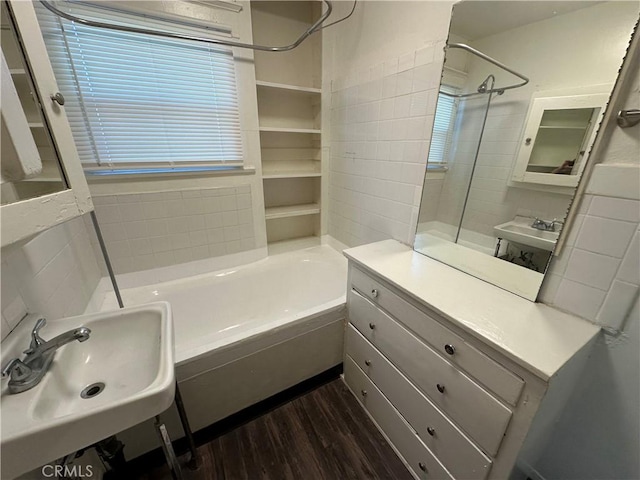 bathroom with tiled shower / bath combo, wood-type flooring, and sink