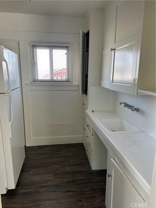 kitchen with white cabinetry, decorative backsplash, dark wood-type flooring, white refrigerator, and sink