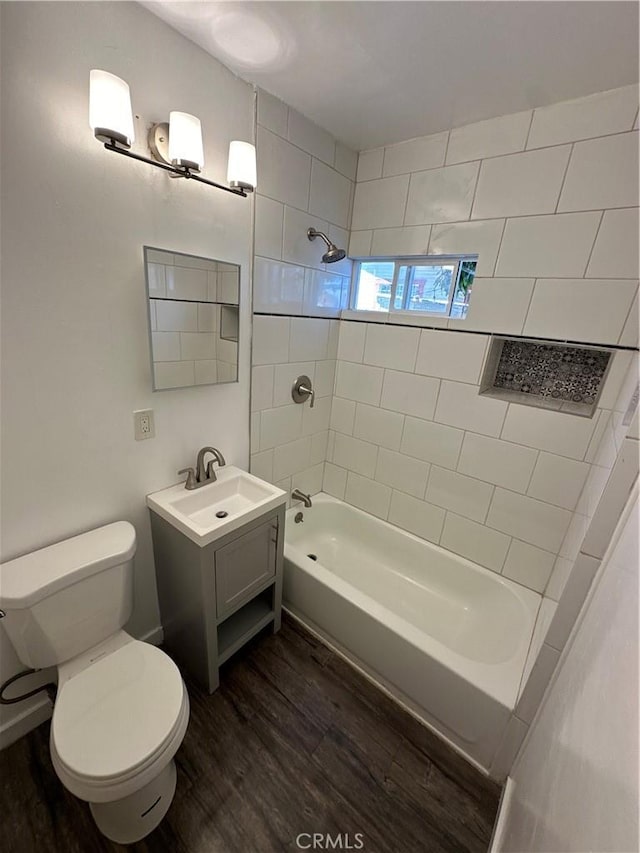 full bathroom with toilet, tiled shower / bath, vanity, and hardwood / wood-style floors