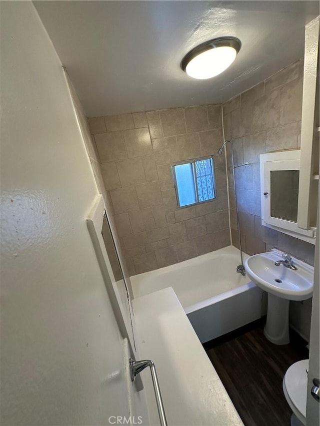 full bathroom with sink, wood-type flooring, toilet, and tiled shower / bath