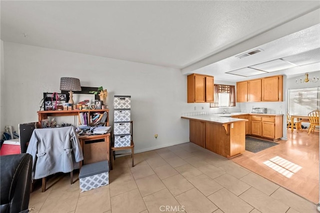 kitchen with light tile patterned flooring, tile counters, a kitchen bar, and kitchen peninsula